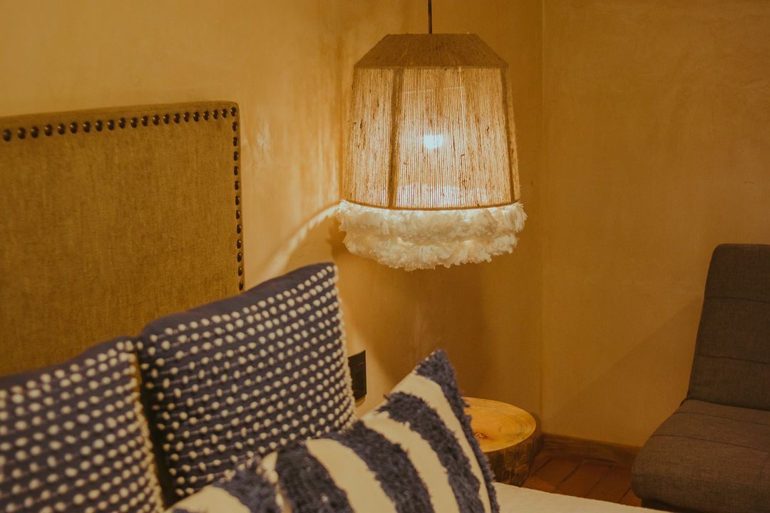 Guest room with arranged cushions, a bedside lamp, and warm lighting