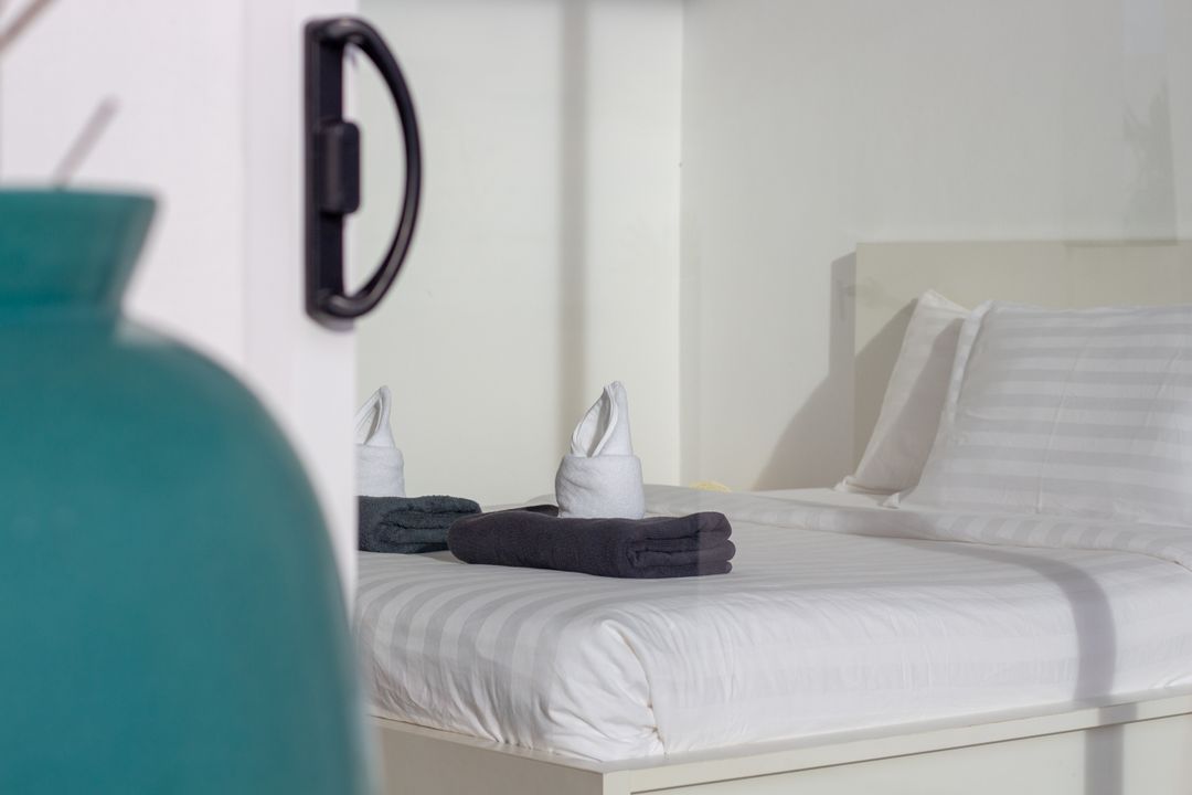 Guest bedroom with neatly made white bedding and folded towels