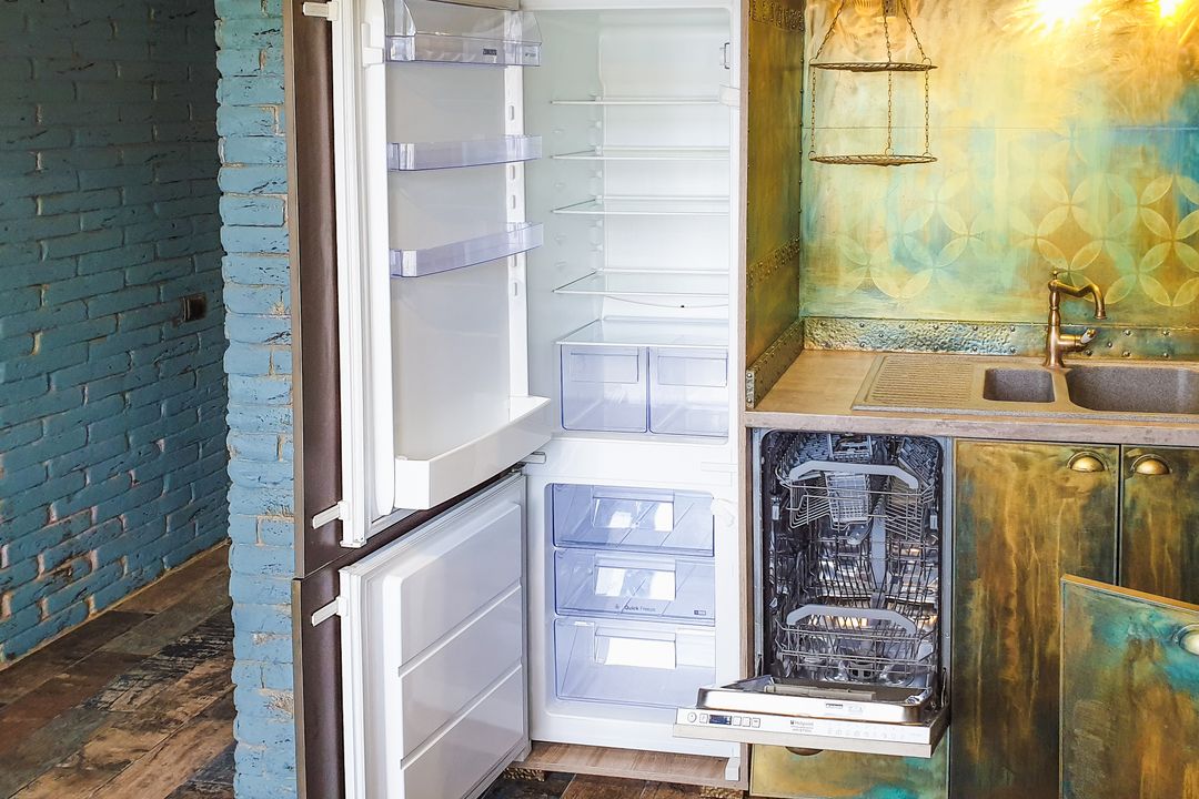 Open refrigerator beside a kitchen sink