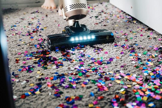 Vacuum cleaner removing colorful debris from a carpet